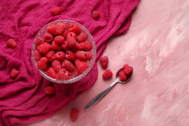 Pembe arka planda taze ahududu olan cam kase.