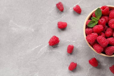 Gri arka planda taze ahududu ve naneli kase, yakın plan.