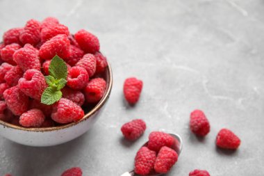 Gri arka planda taze ahududu ve naneli kase, yakın plan.