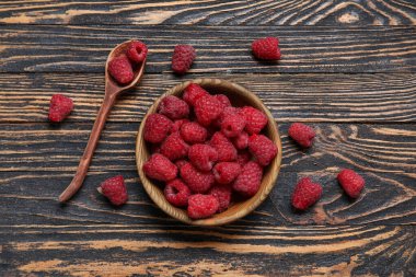 Ahşap arka planda taze ahududu ve kaşıkla kase.