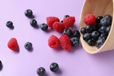 Leylak arkaplanda taze yaban mersini ve ahududu kasesi.