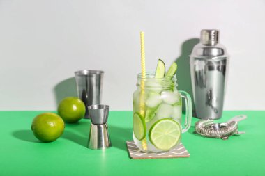 Cam kavanozda mojito kokteyli ve arka planda barmen aletleri.