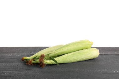 Beyaz arka planda siyah ahşap masada taze mısır koçanları