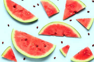 Taze karpuz parçaları ve mavi arka planda tohumlar.