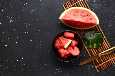 Siyah arka planda taze karpuz parçaları olan bir kase.