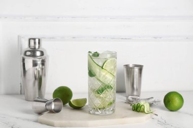 Beyaz arka planda salatalıklı bir bardak mojito.