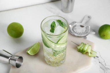 Beyaz arka planda salatalıklı bir bardak mojito.