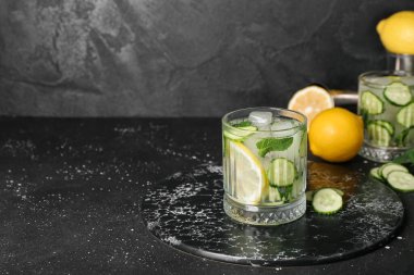 Bir bardak mojito ve grunge black table üzerinde salatalık.