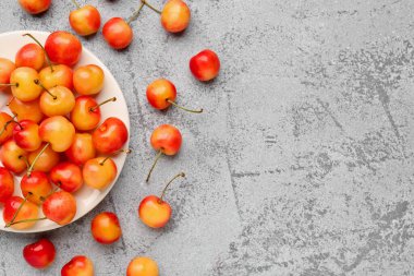 Gri arka planda tatlı sarı kirazlı tepsi