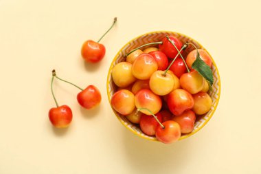 Bej arka planda taze sarı kirazlı kase, yakın plan.