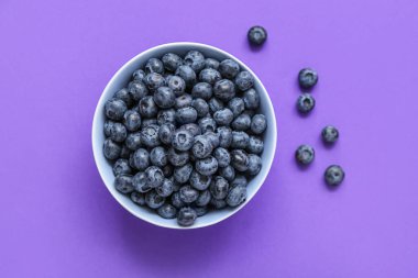 Mor arka planda taze yaban mersinli kase