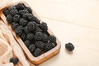 Hafif ahşap zemin üzerinde taze böğürtlen olan tahta, yakın plan.