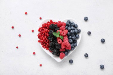 Açık arkaplanda taze böğürtlen tabağı