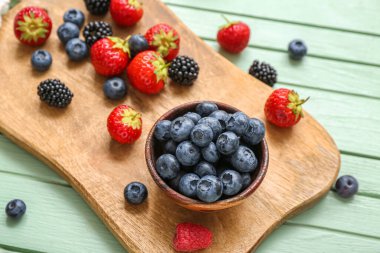Renkli ahşap arka planda farklı taze böğürtlen içeren tahta, yakın plan
