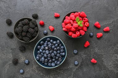 Siyah arka planda taze ahududu, yabanmersini ve böğürtlen kâseleri