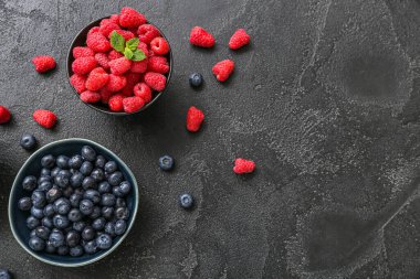 Siyah arka planda taze ahududu ve yaban mersini kaseleri