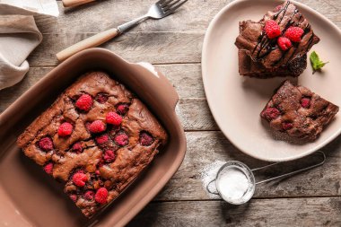 Ahududulu çikolatalı brownie ile ahşap masada yemek tabağı ve tabak.