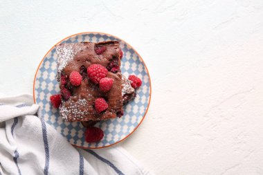 Açık mavi masada ahududulu çikolatalı browni tabağı.