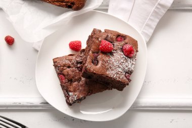 Beyaz arka planda ahududulu çikolatalı browni tabağı.