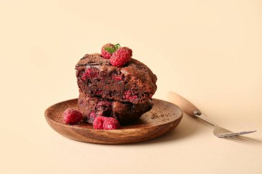 Turuncu arka planda ahududu çikolatalı browni ile ahşap tabak.