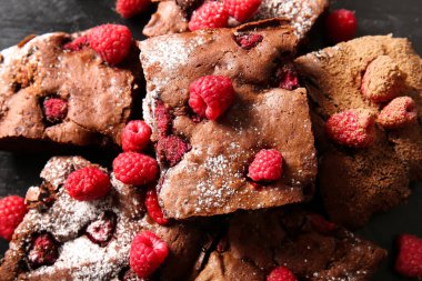 Siyah arkaplanda ahududulu çikolatalı brownie parçaları, yakın plan.