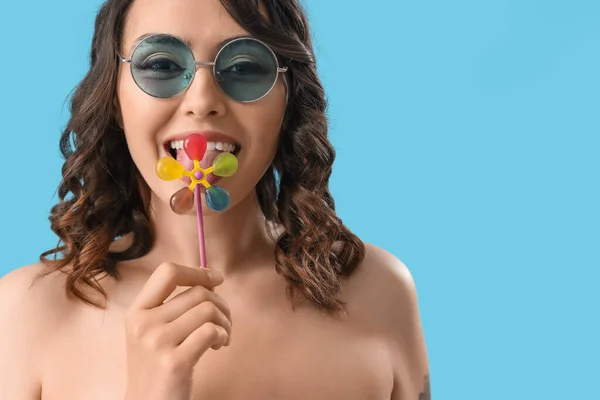 戴太阳镜的年轻女人吃蓝色背景的棒棒糖 特写镜头 — 图库照片