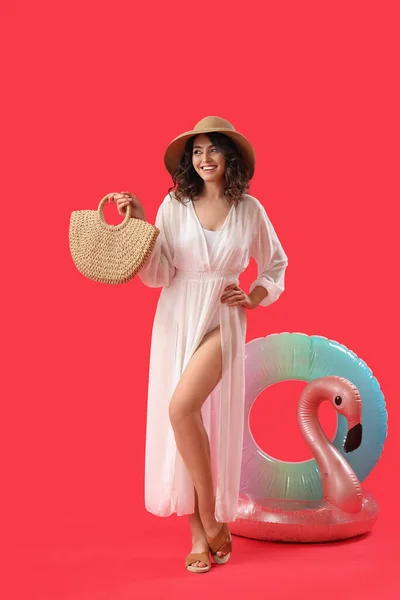Junge Frau Mit Strandtasche Und Aufblasbaren Ringen Auf Rotem Hintergrund — Stockfoto