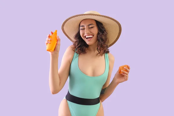 Junge Frau Badeanzug Mit Sonnencreme Auf Fliederfarbenem Hintergrund — Stockfoto