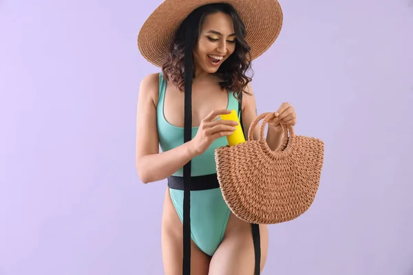 Junge Frau Mit Sonnencreme Strandtasche Auf Fliederfarbenem Hintergrund — Stockfoto