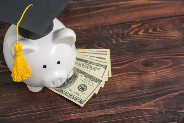 Sparschwein Graduiertenmütze Mit Dollarnoten Auf Braunem Holzgrund Konzept Für Studienkredite — Stockfoto