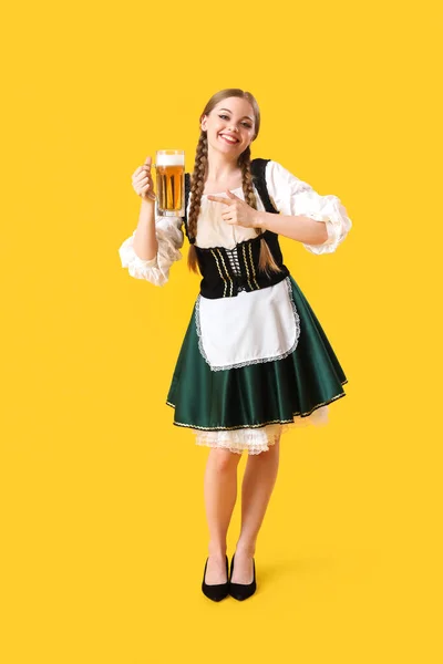 아름다운 페스트 웨이트리스가 노란색 배경의 맥주를 가리키는 — 스톡 사진