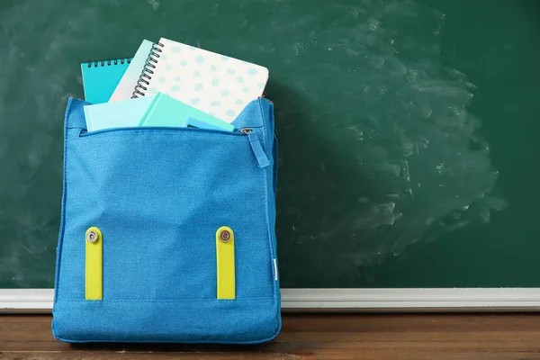 Μπλε Σχολική Τσάντα Πλάτης Σημειωματάρια Ξύλινο Τραπέζι Κοντά Πράσινο Πίνακα — Φωτογραφία Αρχείου