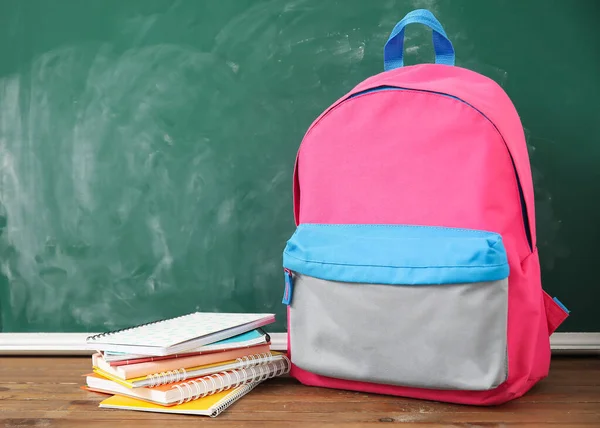 Ροζ Σχολική Τσάντα Πλάτης Σημειωματάρια Ξύλινο Τραπέζι Κοντά Πράσινο Πίνακα — Φωτογραφία Αρχείου