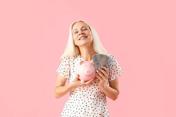 有美元钞票和粉色背景的储蓄罐的成熟女人 — 图库照片
