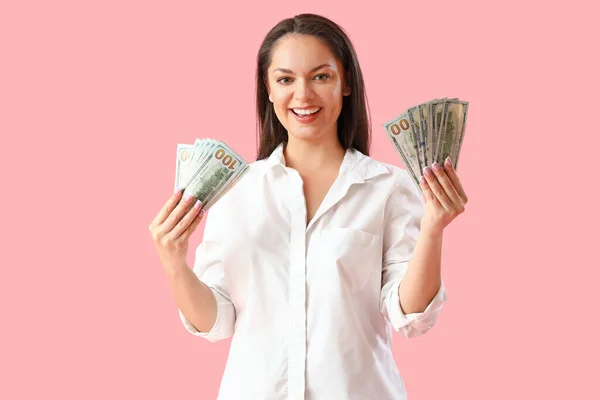 ピンクの背景にドル紙幣を持つ若い女性 — ストック写真