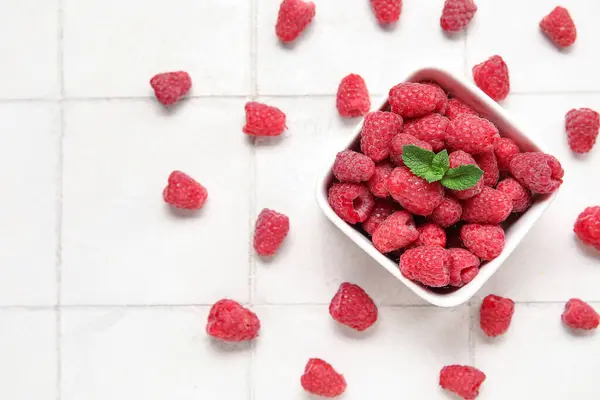 stock image Bowl with fresh raspberry and mint on light tile background, closeup