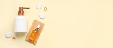 Sıvı sabun şişeleri ve bej arkaplan üzerinde spa taşları olan serumlar.