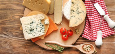 Ahşap arka planda farklı peynir çeşitleri olan tahta.