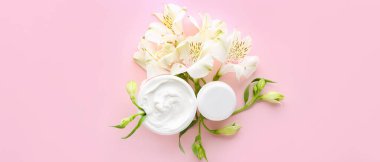 Kavanozda doğal krema, pembe arka planda çiçekler