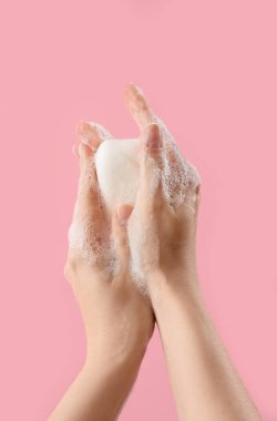 Pembe arka planda sabunlu eller