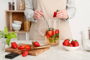 Kadın mutfakta çilekli limonata hazırlıyor.