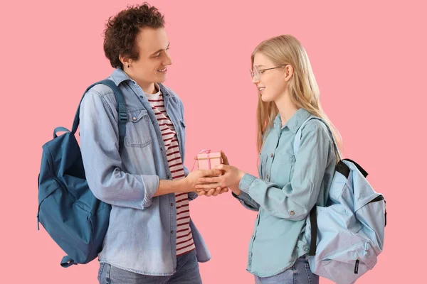 十几岁的男孩带着粉色背景的礼物问候他的女朋友 — 图库照片