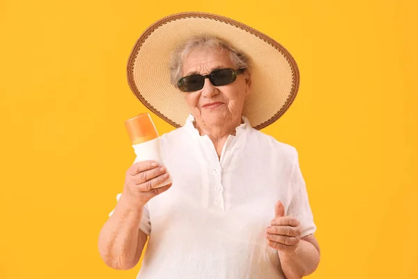 オレンジの背景に日焼け止めクリームを持つシニア女性 — ストック写真