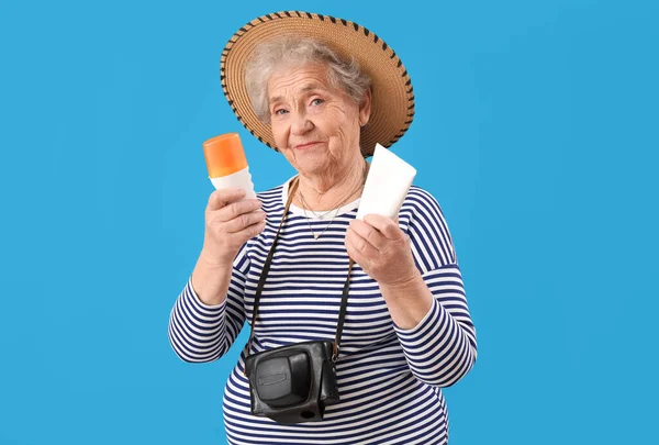 青の背景に日焼け止めクリームを持つシニア女性 — ストック写真