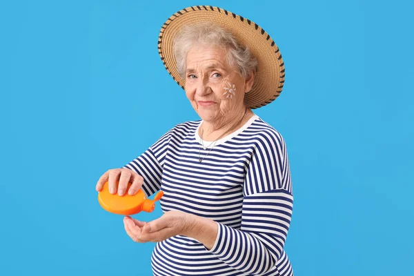 Senior Woman Applying Sunscreen Cream Blue Background — Stock Photo, Image