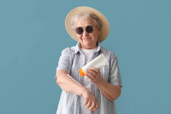 Seniorin Trägt Sonnencreme Auf Blauem Hintergrund Auf — Stockfoto