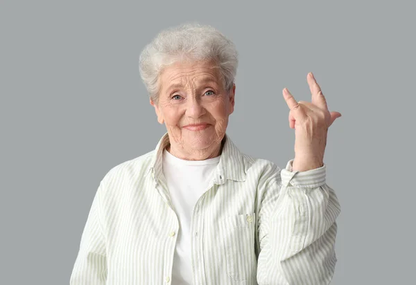 Seniorin Zeigt Ich Liebe Dich Geste Auf Grauem Hintergrund — Stockfoto