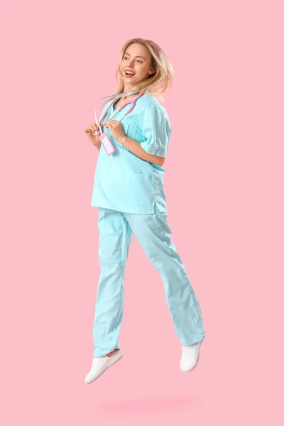 女性实习医生在粉色背景下跳跃 — 图库照片
