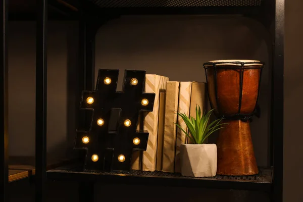 暗い部屋の棚に本 植物やドラムでランプを光る — ストック写真