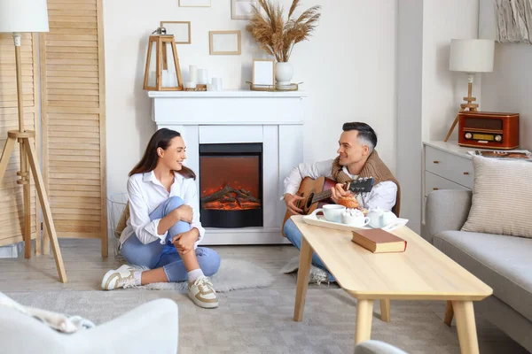 Young Woman Her Husband Playing Guitar Fireplace Home — Stock Photo, Image
